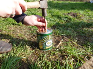 Hammering a nail in the lid - Charcoal Making - Pippin & Gile Bushcraft Courses and Foraging Courses