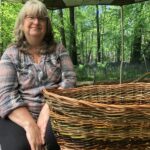 A smiling woman with a beautiful completed hand made willow basket