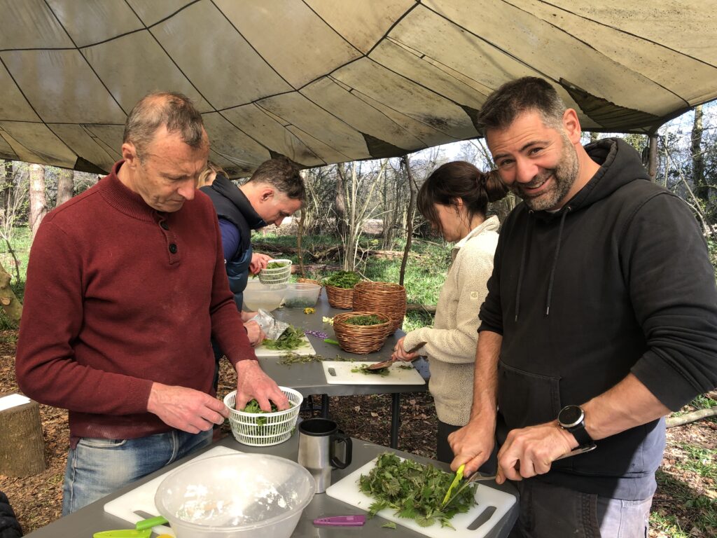 a mixed group of people preparing wild greens outside on a foraging course