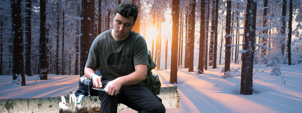a person carving with knife and a winter woodland background