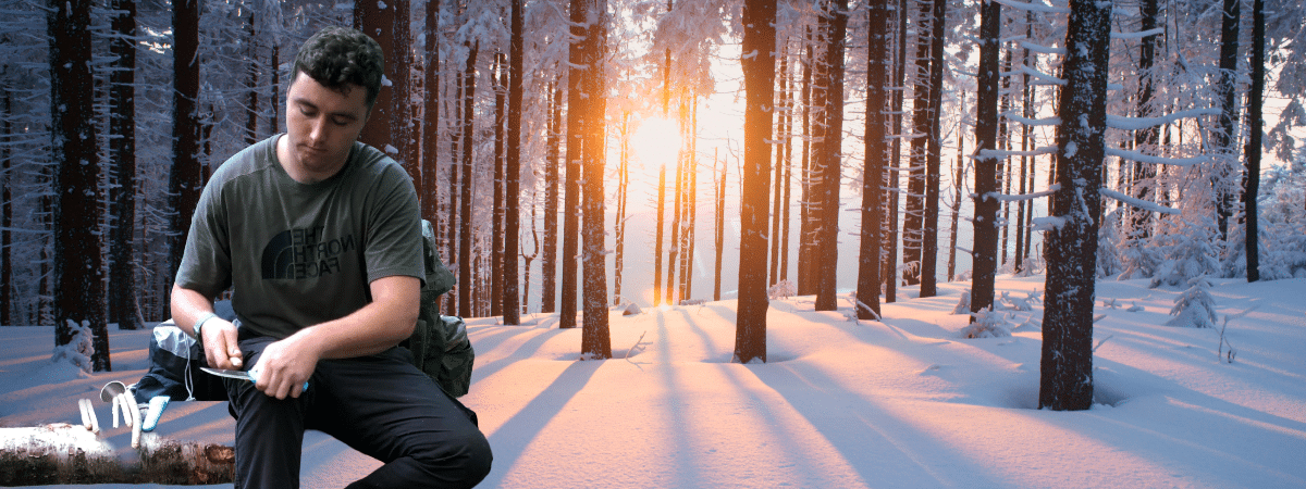 a person carving with knife and a winter woodland background 