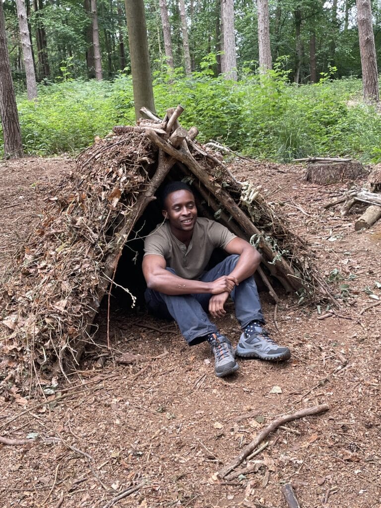 Men sitting happily in shelter on bushcraft and survival course